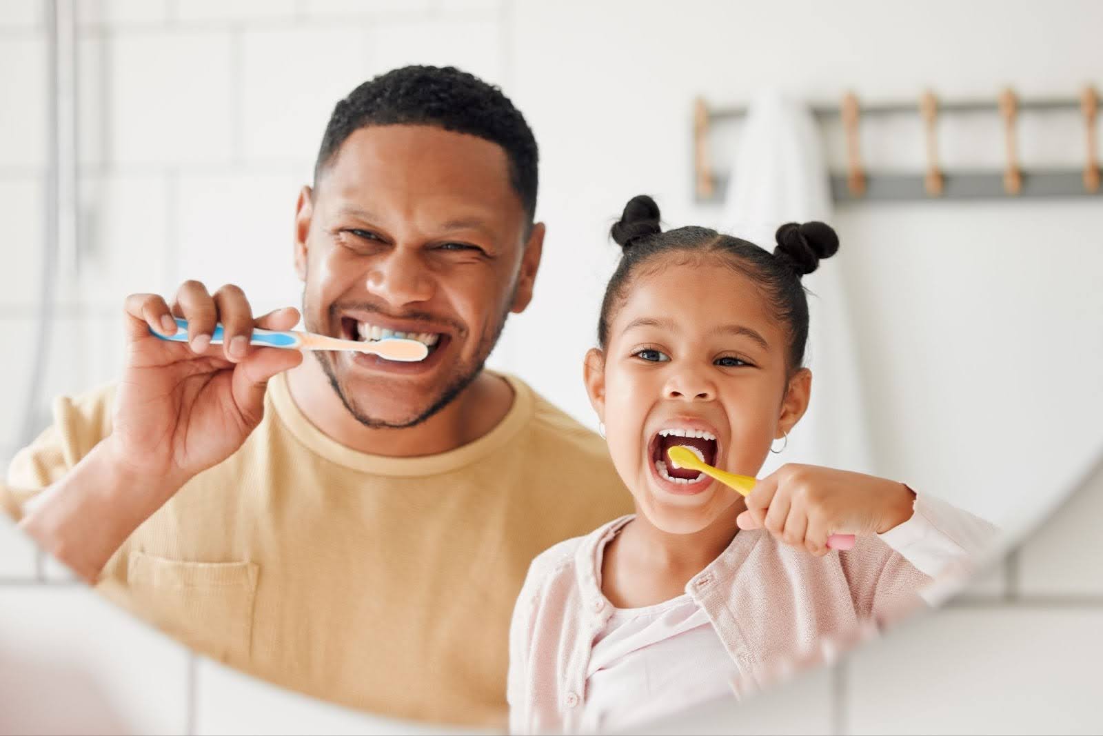 Father and daughter brushing teeth to prevent sensitive teeth symptoms